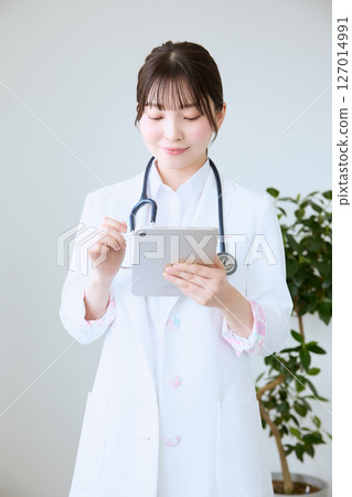 A female doctor writing a medical record on a tablet at a clinic 127014991