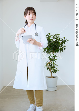 A female doctor writing a medical record on a tablet at a clinic 127014993