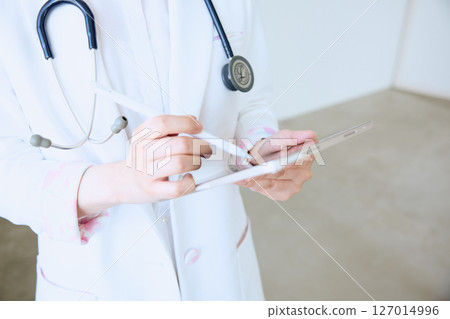 一位女醫生在診所的平板電腦上寫下病歷 127014996