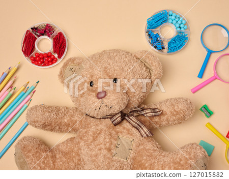 brown teddy bear is surrounded by various colorful school supplies on a neutral background brown teddy bear is surrounded by various colorful school supplies on a neutral background 127015882