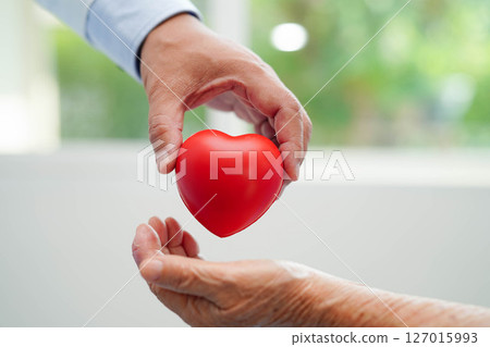 Asian elder senior woman patient holding red heart in hospital. Asian elder senior woman patient holding red heart in hospital. 127015993