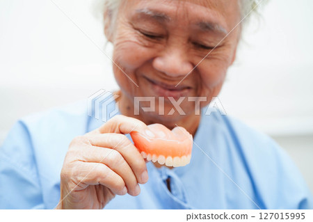 Doctor holding teeth denture in hand for dentist studying about dentistry. 127015995