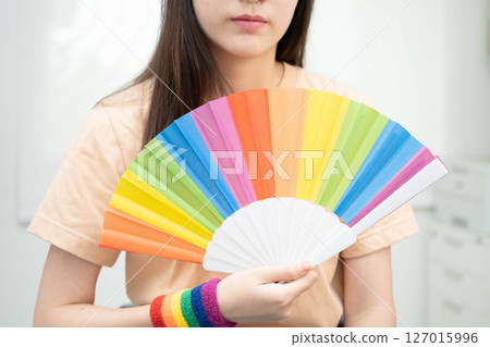 Asian woman holding LGBT rainbow flag. 127015996
