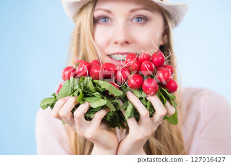 woman holding radish close to face 127016427