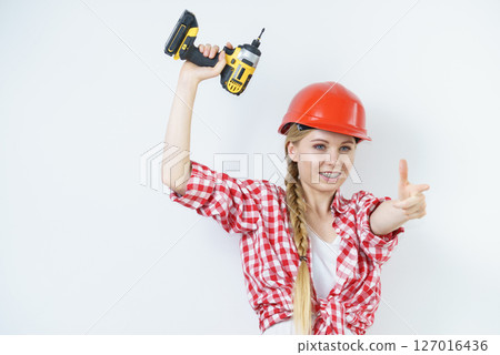 Woman wearing helmet using drill 127016436
