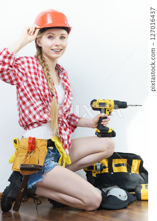 Woman wearing helmet using drill 127016437