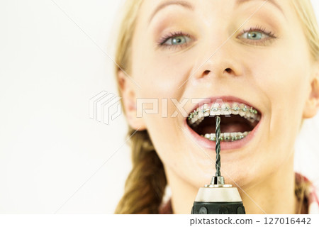 Woman with braces pointing with drill Woman with braces pointing with drill 127016442