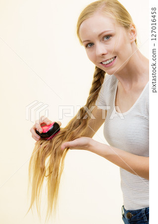 Blonde girl with long braid hair holds brush 127016458