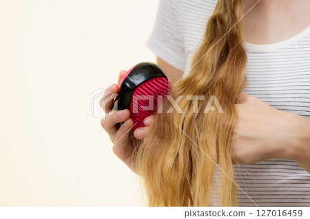 Blonde girl brushing her long hair 127016459