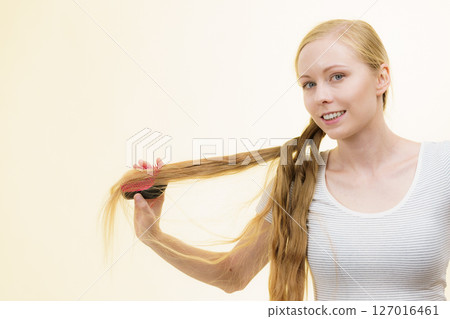 Blonde girl brushing her long hair Blonde girl brushing her long hair 127016461