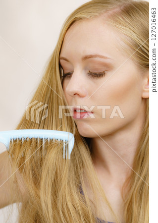Woman combing long healthy blonde hair Woman combing long healthy blonde hair 127016463
