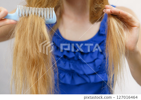 Blonde girl combing her long messy hair Blonde girl combing her long messy hair 127016464