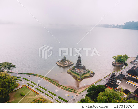 Drone view of Ulun Danu Beratan Temple in Bali surrounded by misty lake and lush landscape, peaceful and iconic scene. 127016704