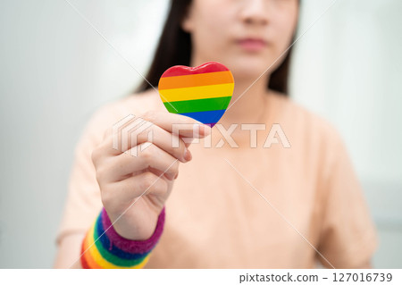 Asian woman holding LGBT heart with rainbow flag. 127016739