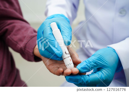 Asian senior woman using lancet pen on senior patient finger for check sample blood sugar level to treatment diabetes. 127016776