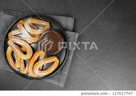 Traditional spanish dessert churros, fried dough pastry and chocolate sause on black background Traditional spanish dessert churros, fried dough pastry and chocolate sause on black background 127017747
