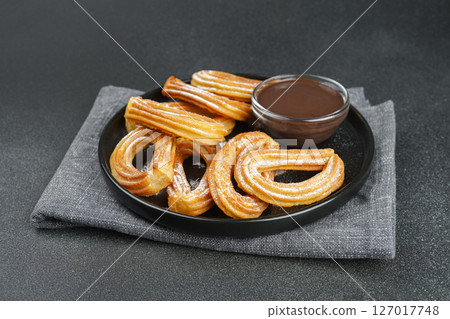 Traditional spanish dessert churros, fried dough pastry and chocolate sause on black background 127017748
