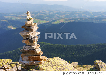 Stacked rock cairn on mountain peak with Carpathian view background. Travel and hiking exploration 127017773