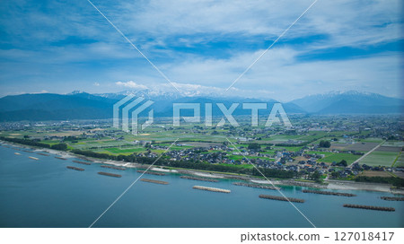 A view of the humid coast of Toyama Prefecture, Japan, with its surrounding offshore breakwaters and offshore wind turbines during the rainy season. A view of the humid coast of Toyama Prefecture, Japan, with its surrounding offshore breakwaters and offshore wind turbines during the rainy season. 127018417