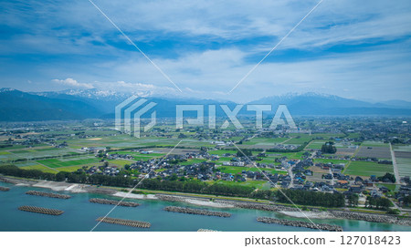 A view of the humid coast of Toyama Prefecture, Japan, with its surrounding offshore breakwaters and offshore wind turbines during the rainy season. 127018423
