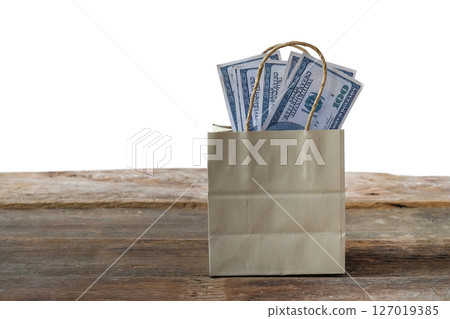 Dollars money in paper bag on wood table. Dollars money in paper bag on wood table. 127019385
