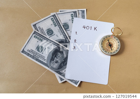 401k  Plan and Gold compass on pile of US money. 127019544