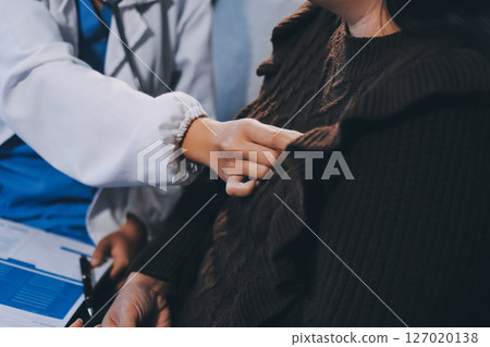 Homecare nursing service and elderly people cardiology healthcare. Close up of young hispanic female doctor nurse check mature caucasian man patient heartbeat using stethoscope during visit Homecare nursing service and elderly people cardiology healthcare. Close up of young hispanic female doctor nurse check mature caucasian man patient heartbeat using stethoscope during visit 127020138