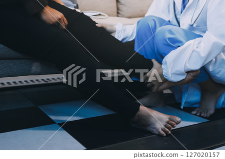 Young doctor examines senior patient's leg 127020157
