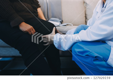 Young doctor examines senior patient's leg 127020159