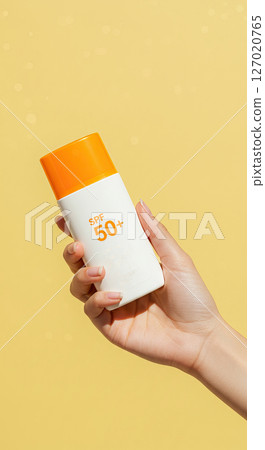 Sun protection concept with spf 50 plus bottle on bright yellow background 127020765