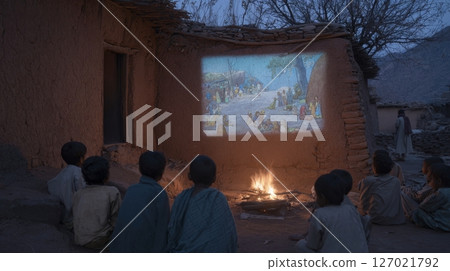 Tribal kids watch an animated film in their native language by firelight and digital glow 127021792