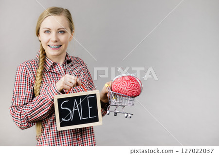 Woman holding shopping cart with brain and sale Woman holding shopping cart with brain and sale 127022037