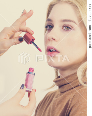 Woman applying lipstick or lip gloss Woman applying lipstick or lip gloss 127022345