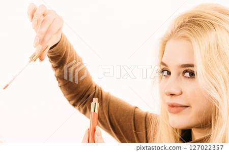 Happy cheerful woman using lips gloss Happy cheerful woman using lips gloss 127022357