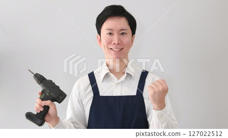 一名男子穿著圍裙，手持鑽頭，展現他的勇氣 127022512