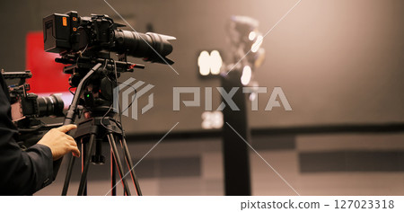 Professional cinema cameras being used in a studio or event setting. High end gear with crew operation and behind the scenes video production in action. Camera for Live recording and broadcasting. Professional cinema cameras being used in a studio or event setting. High end gear with crew operation and behind the scenes video production in action. Camera for Live recording and broadcasting. 127023318