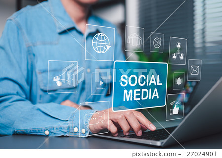 Social Media Marketing and Digital Engagement Concept. A person using laptop with virtual icons and words Social Media, symbolizing online marketing, content sharing, digital communication strategies, 127024901