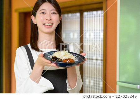 一位女士開心地舉著一盤日本料理，露出燦爛的笑容 127025249