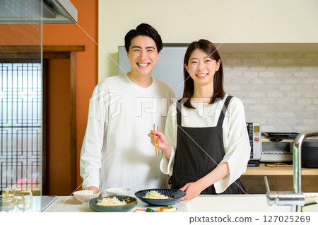 明亮而平靜的日常廚房場景，男女面帶微笑地站著 127025269