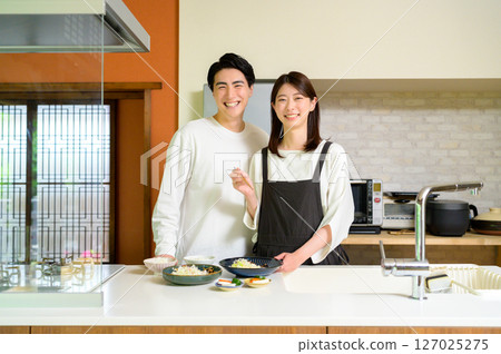 男人和女人微笑著並肩站在廚房裡，這是一個平靜的日常場景 127025275