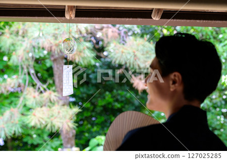 A quiet moment captured in the profile of a man gazing at wind chimes A quiet moment captured in the profile of a man gazing at wind chimes 127025285