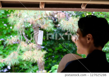 A quiet afternoon for a man looking at wind chimes in natural light A quiet afternoon for a man looking at wind chimes in natural light 127025286