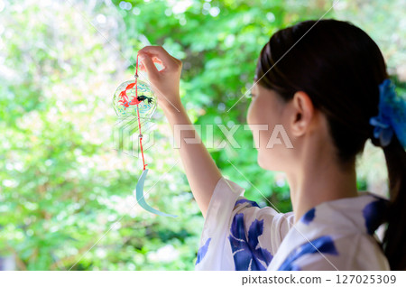 A quiet moment reflected in the back of a woman in a yukata gazing at summer wind chimes A quiet moment reflected in the back of a woman in a yukata gazing at summer wind chimes 127025309