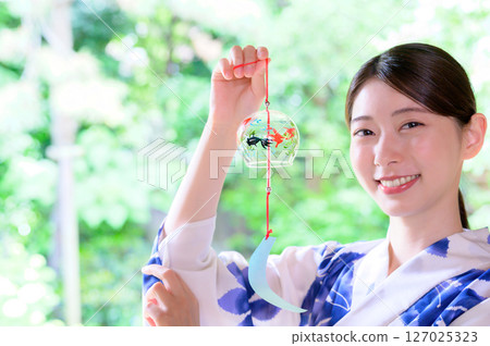 綠色背景下，一位身穿浴衣、微笑的女子手持風鈴 127025323