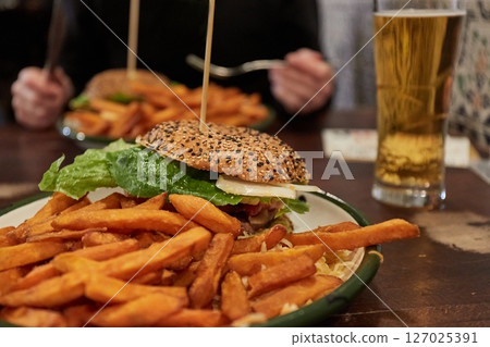 Eating hamburger and fries in restaurant Eating hamburger and fries in restaurant 127025391