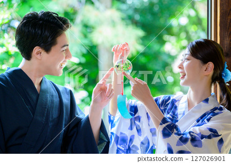 A summer scene of men and women in yukata laughing happily against a background of greenery 127026901