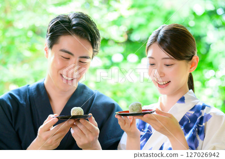 A peaceful summer scene of men and women in yukata showing each other Japanese sweets A peaceful summer scene of men and women in yukata showing each other Japanese sweets 127026942