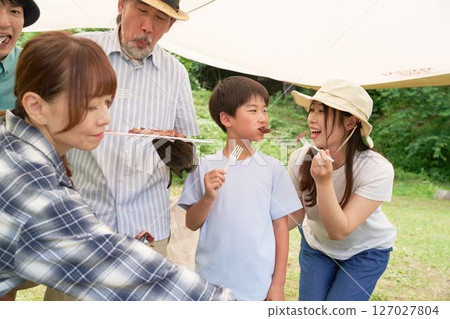 Camping friends enjoying outdoor cooking Camping friends enjoying outdoor cooking 127027804