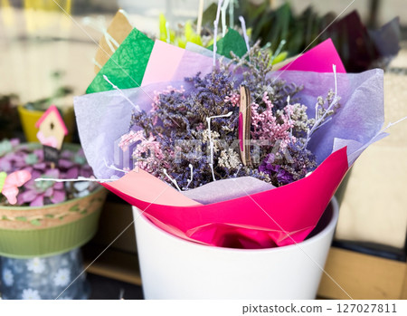 Bouquet of dried flowers in pink wrapping. Mixed lavender, pink, and lilac stems arranged in decorative packaging. Bouquet of dried flowers in pink wrapping. Mixed lavender, pink, and lilac stems arranged in decorative packaging. 127027811