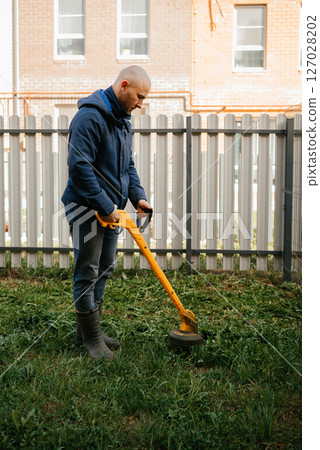 Person Operating Yellow Drill for Garden Maintenance 127028202